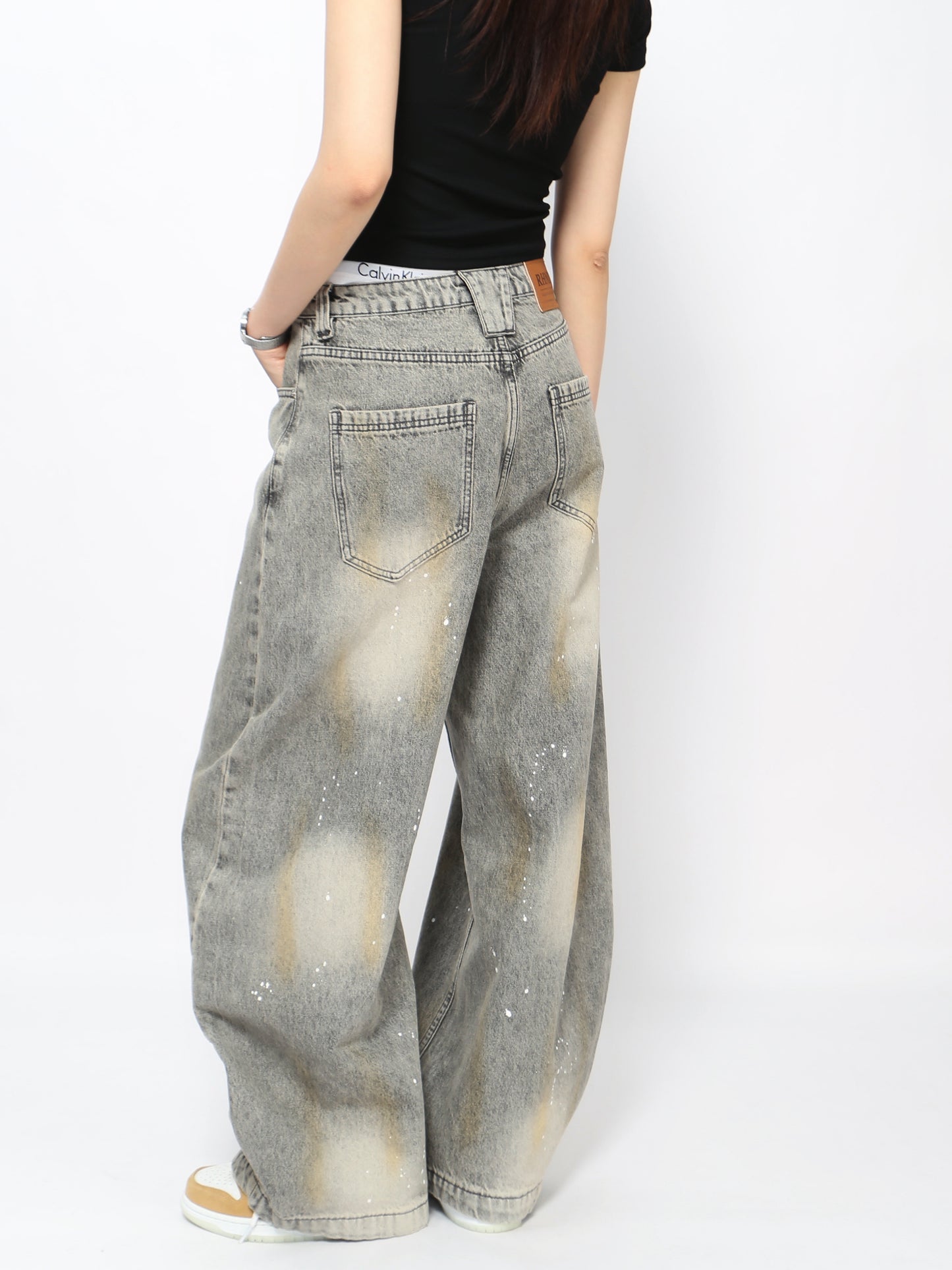 Jeans grises lavados con diseño curvo y salpicaduras, estilo urbano vintage